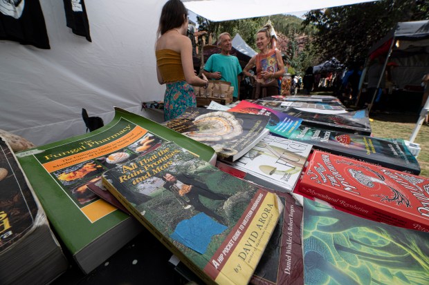 Anna Brown, left, of Boulder Colo., talks with a customers about mushroom treatments with many books for sale during the 43rd Telluride Mushroom Festival held in Telluride Colo., Sunday, August 20, 2023. (Photo by William Woody/Special to The Denver Post)
